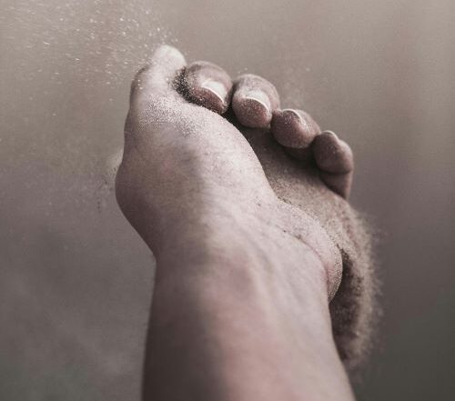 Hand holding sand slipping away